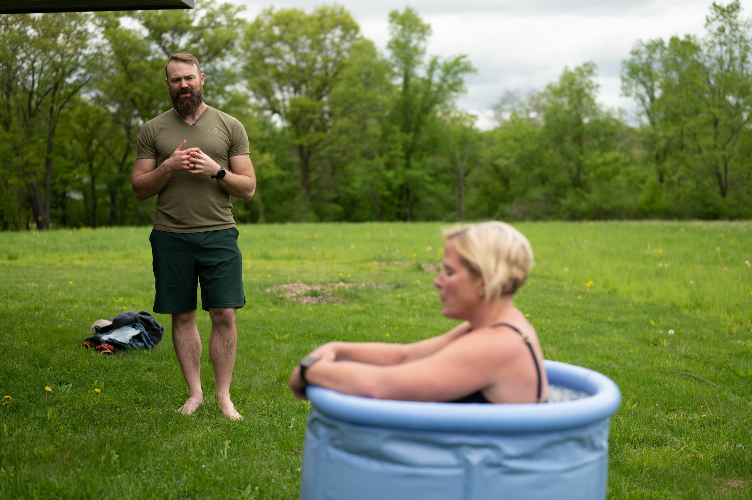 Man watching woman in an ice bath in the woods