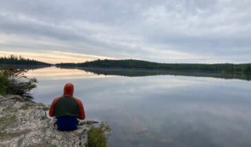 Man meditating while overlooking calm waters